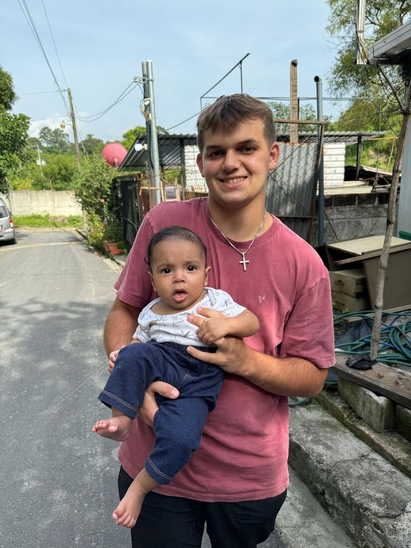 A Pleasant Grove team member holding a young El Salvadoran child on a village street
