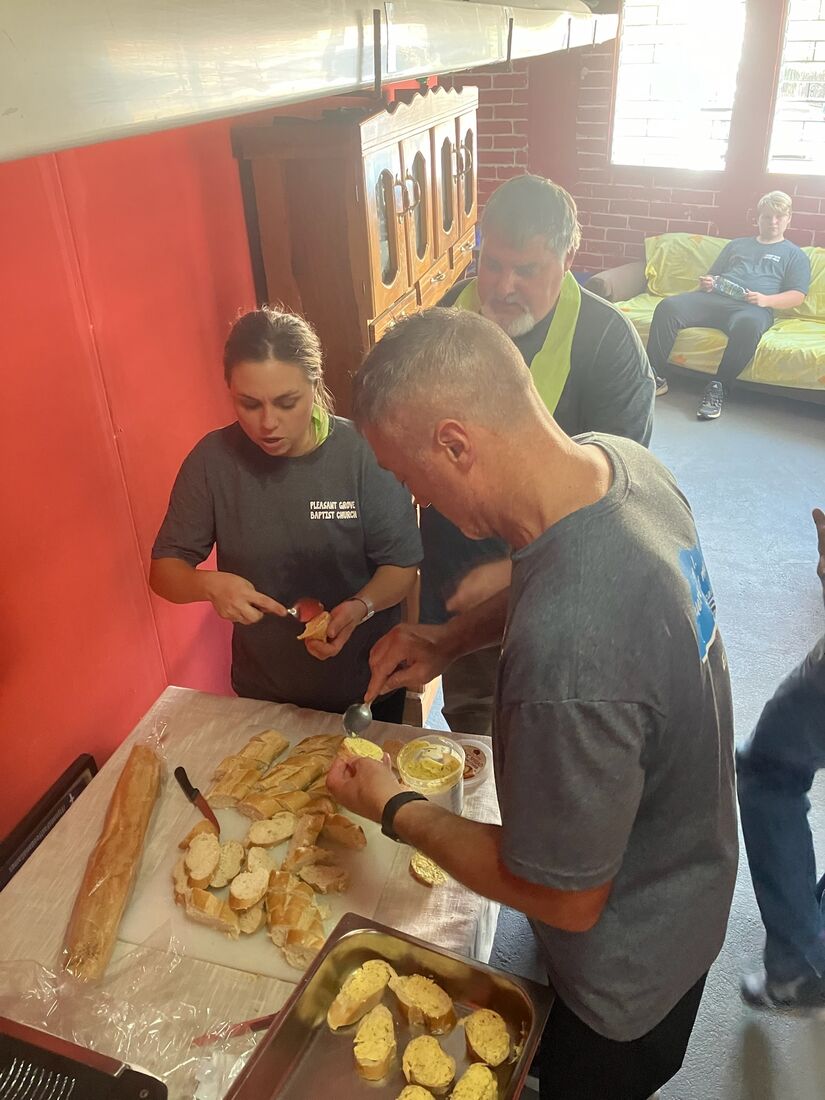 Two team members preparing food together in a church kitchen in El Salvador