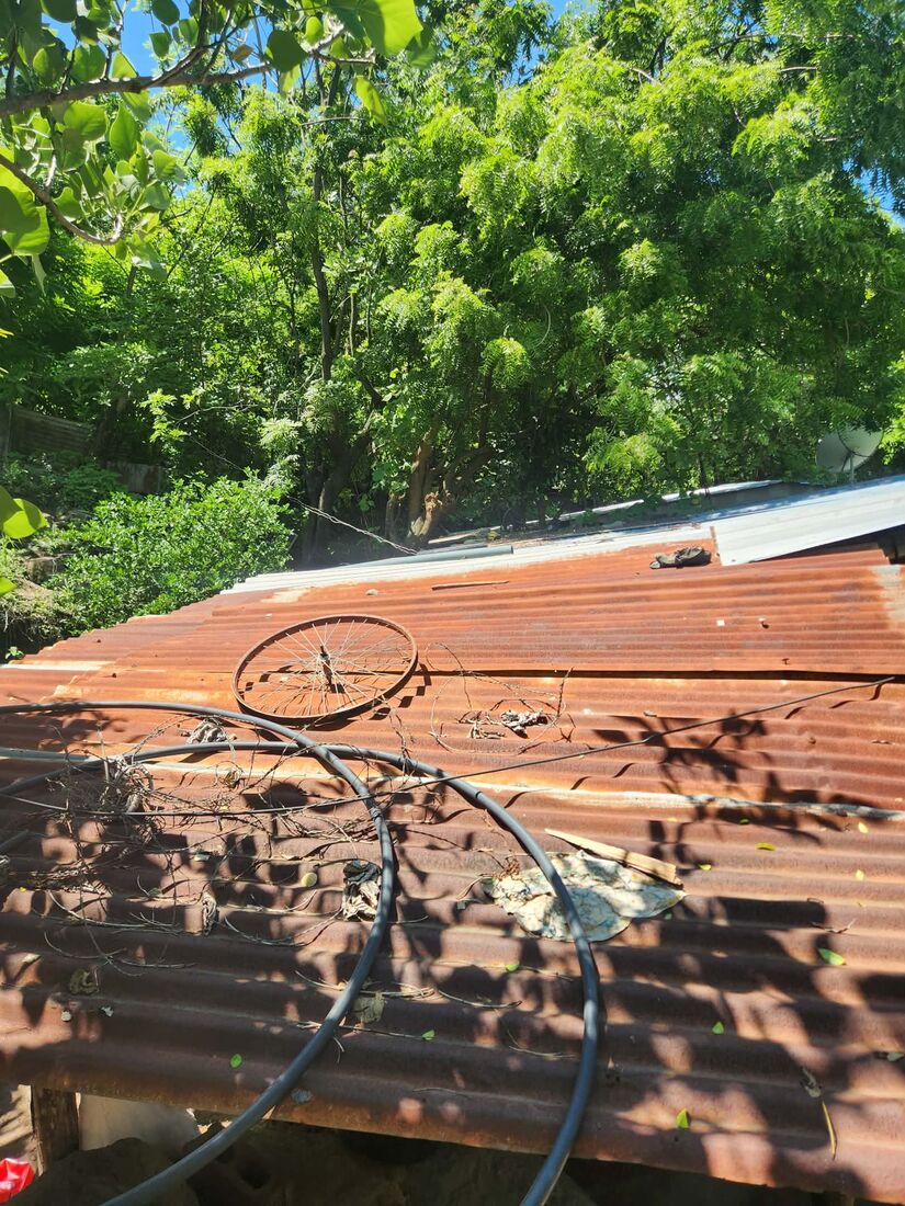 A heavily rusted corrugated metal roof with exposed wiring, in need of replacement and reinforcement